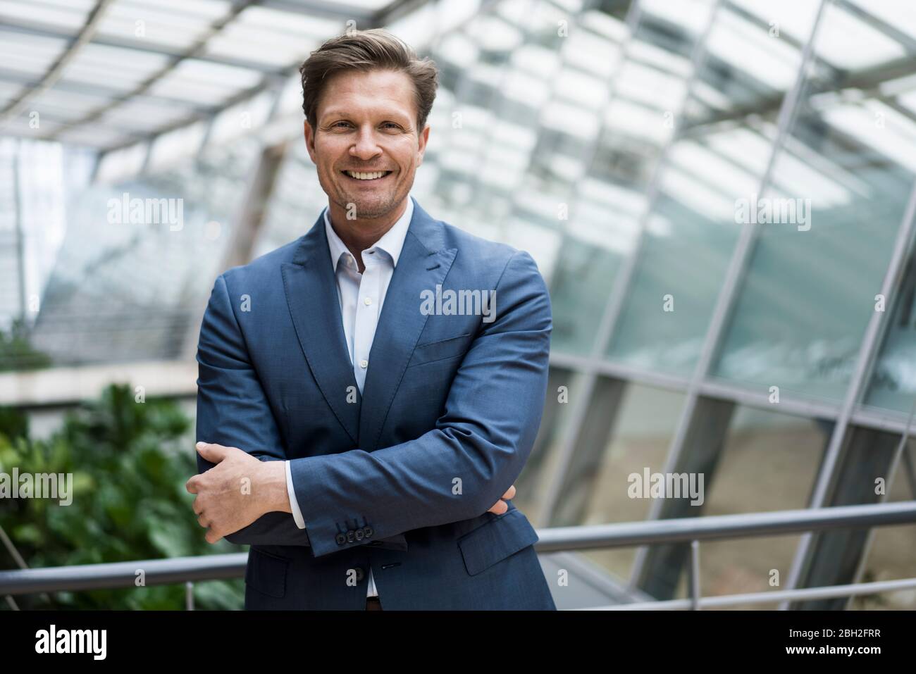 Porträt eines lächelnden Geschäftsmannes im grünen Atrium Stockfoto