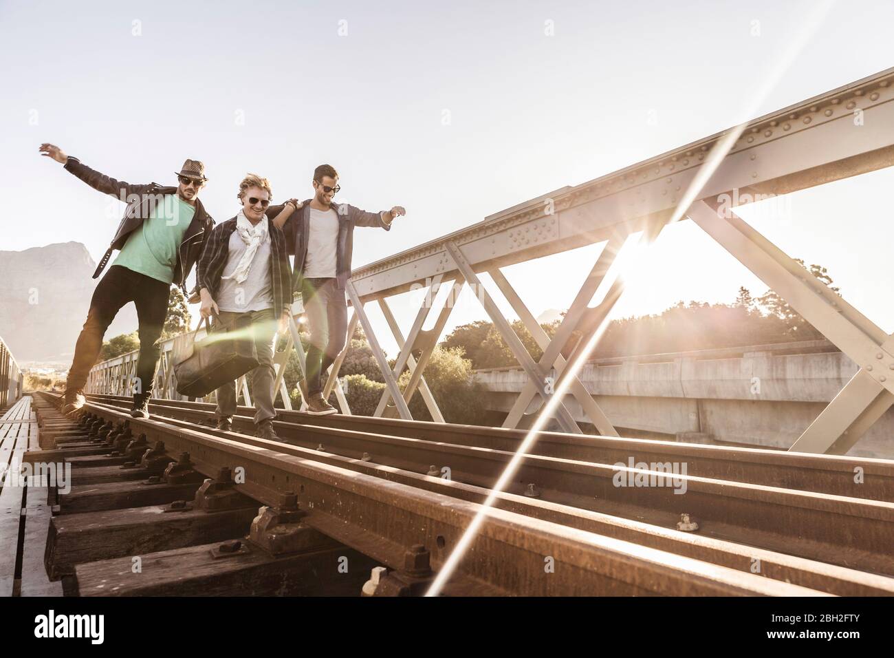 Drei Männer gehen auf einer alten Eisenbahnbrücke Stockfoto