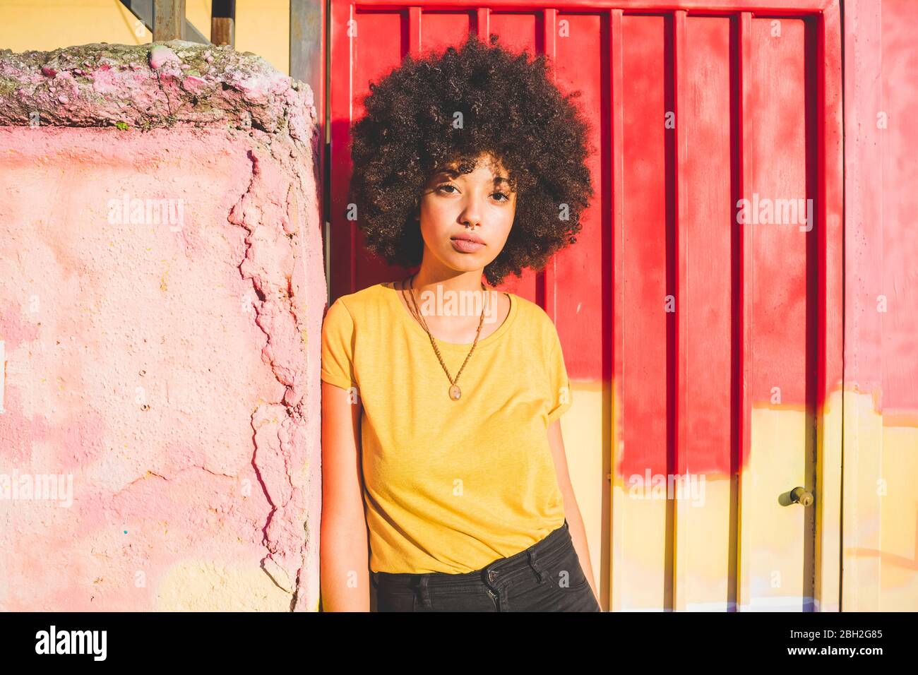 Porträt einer jungen Frau mit afro Frisur an einer Wand gelehnt Stockfoto