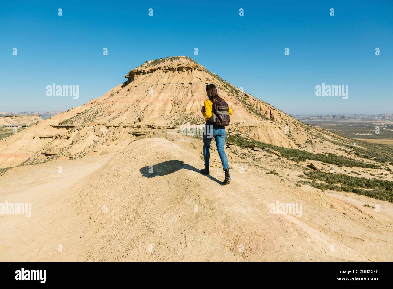 Frau, die in der desertischen Landschaft von Bardenas Reales, Arguedas, Navarra, Spanien, spazierengeht Stockfoto