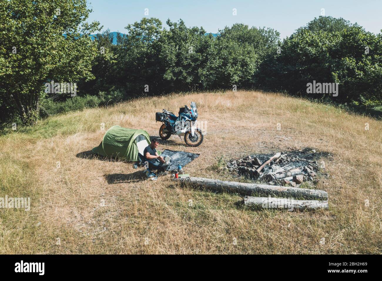 Mann auf einer Motorradtour Camping auf einer abgelegenen Wiese Stockfoto