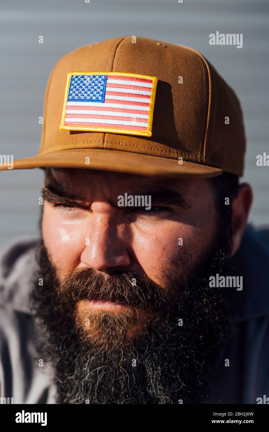 Porträt eines bärtigen Mannes mit Baseballmütze und amerikanischer Flagge Stockfoto