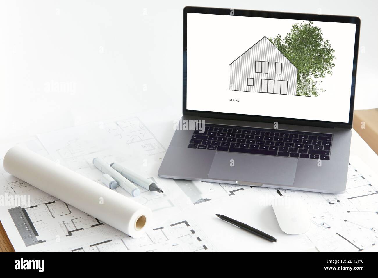 Architektur-Modell des Eigenheims mit Baum auf dem Bildschirm des Laptops, Bauplan Stockfoto