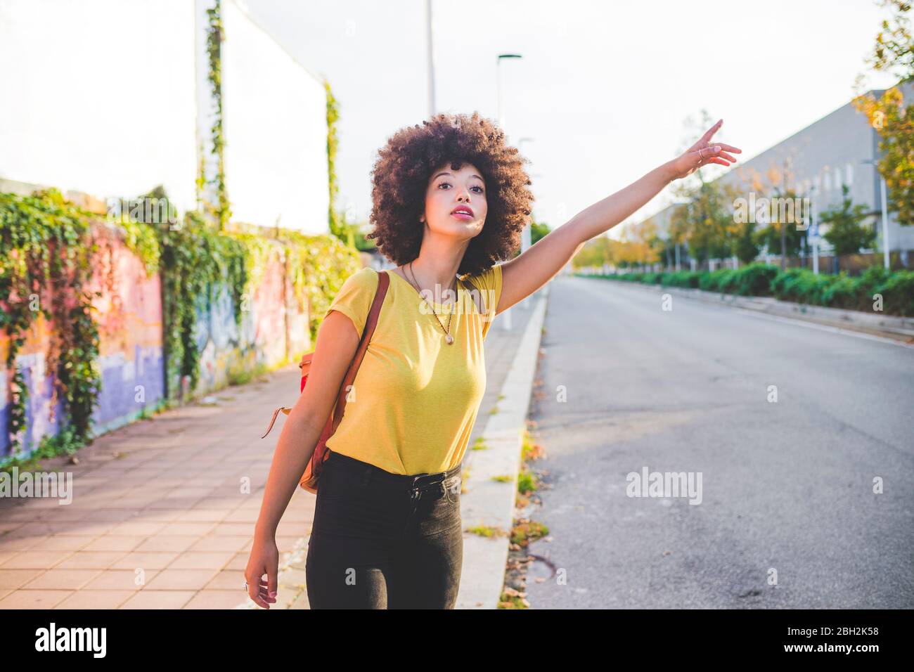 Junge Frau mit afro Hairdo Anhalter in der Stadt Stockfoto