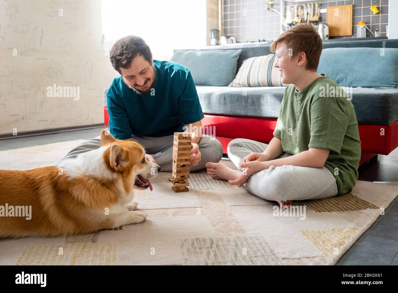 Vater und Sohn bauen Turm mit Holzziegeln auf dem Boden zu Hause Stockfoto