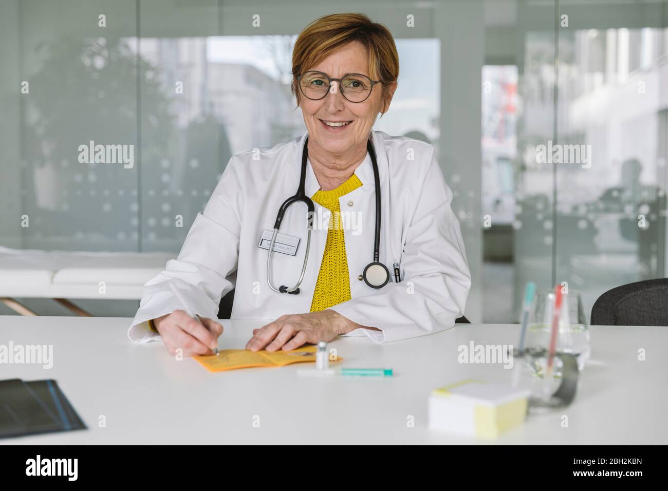 Porträt eines lächelnden Arztes, der die Impfkarte ausfüllt Stockfoto