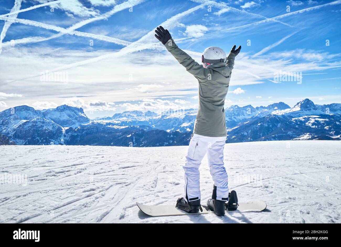 Reife Frau mit Snowboard auf Skipiste mit erhobenen Armen Stockfoto