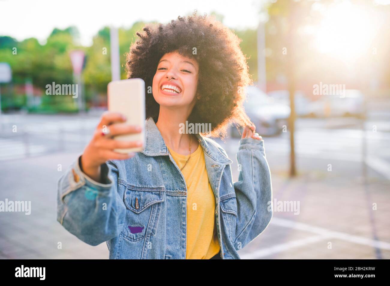 Glückliche junge Frau mit Afro-Frisur, die ein Selfie in der Stadt macht Stockfoto