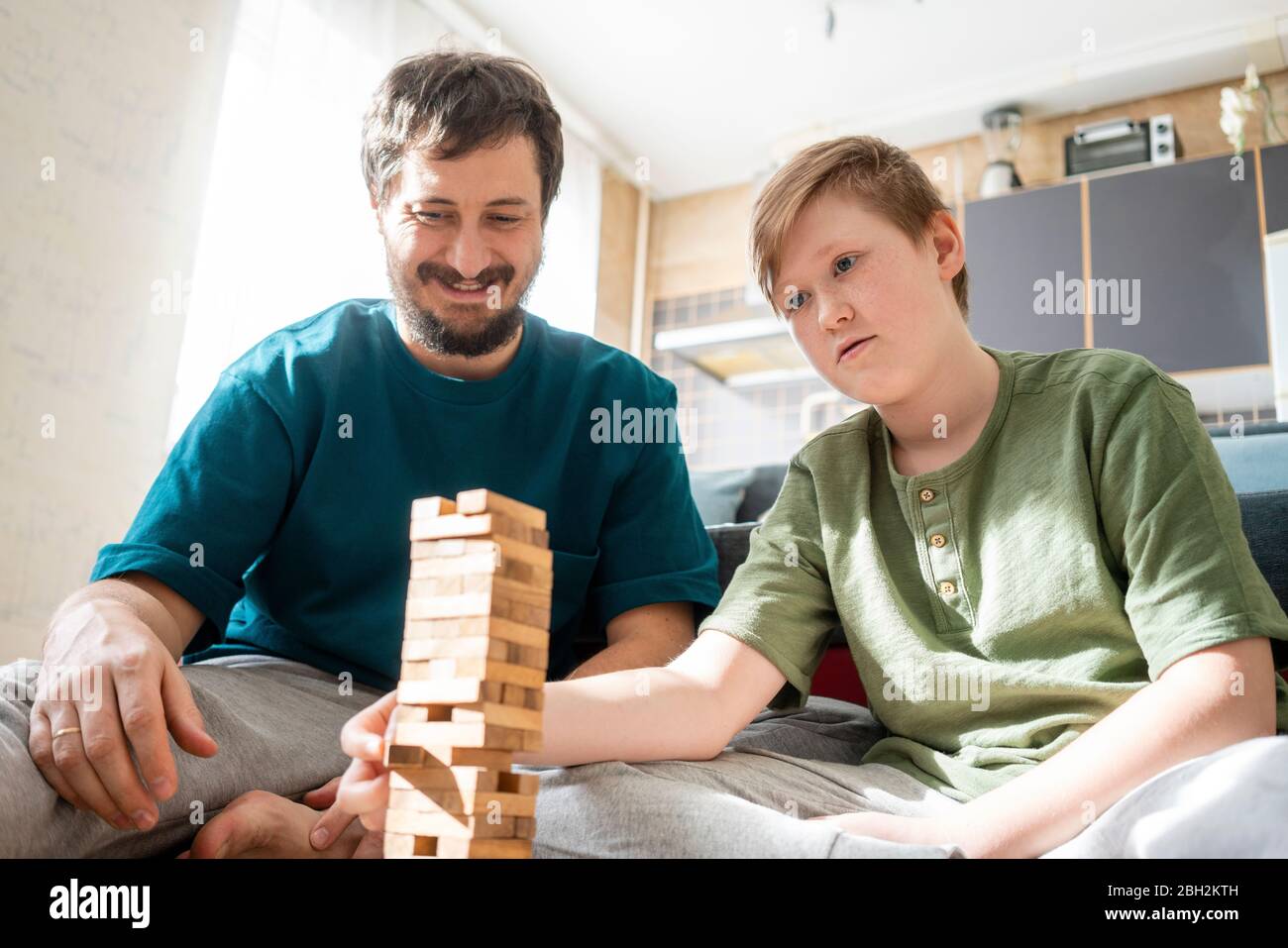 Portrait von Vater und Sohn, der zu Hause einen Turm mit Holzziegeln baut Stockfoto