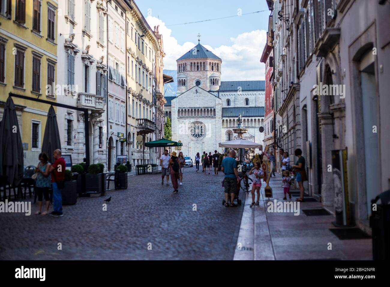 Trento, Italien - 15. August 2019: Menschen, die in der Altstadt von Trento spazieren gehen, mit der St. Vigil Kathedrale im Hintergrund Stockfoto