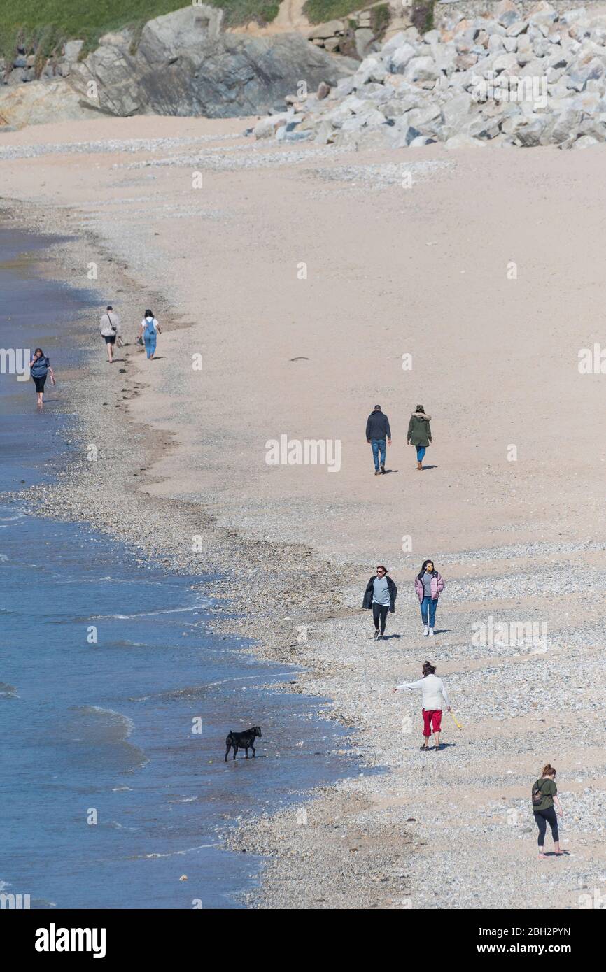 Menschen, die am Fistral Beach in Cornwall spazieren und die soziale Distanz aufgrund der Coronavirus Covid 19 Pandemie aufrechterhalten. Stockfoto