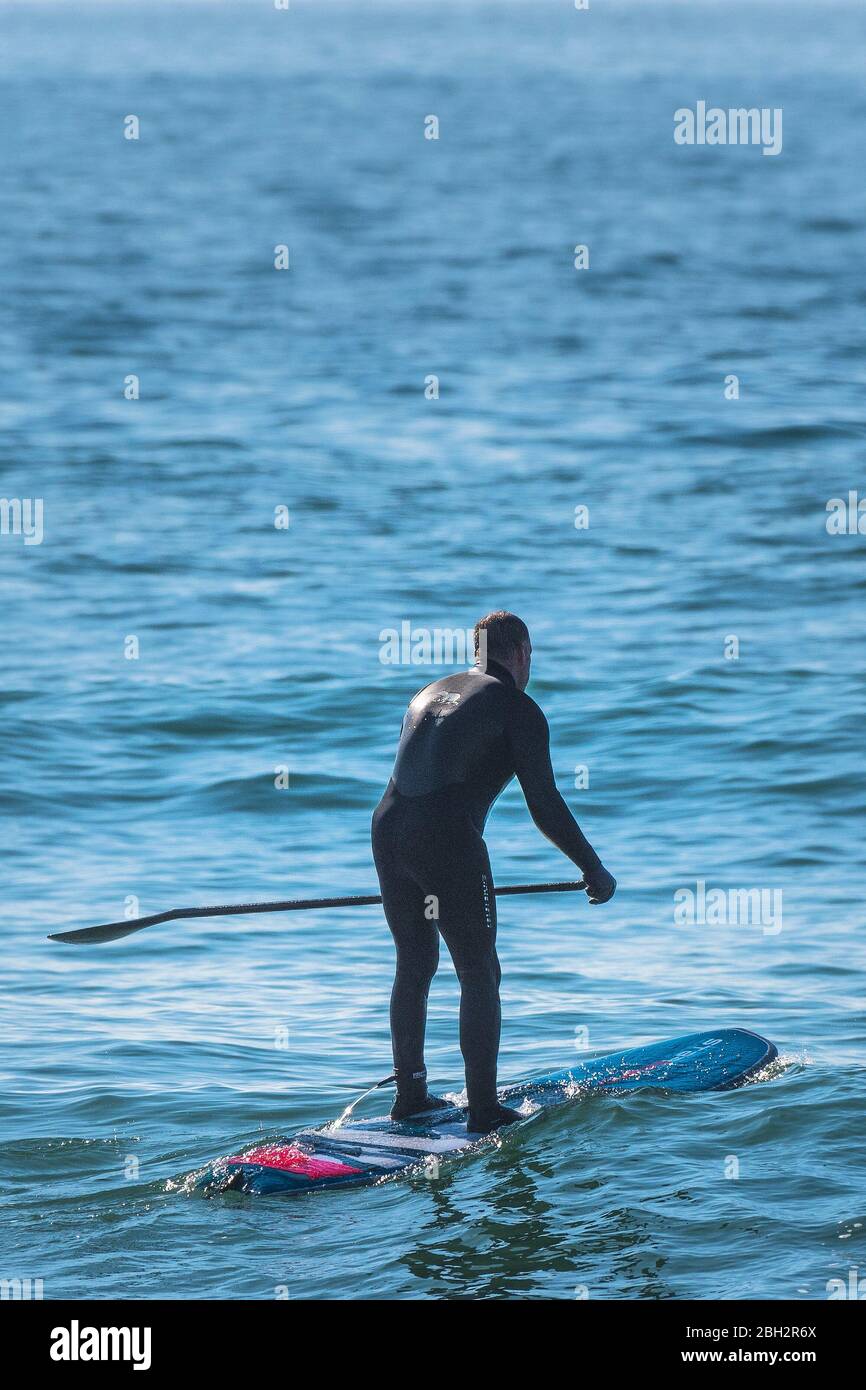 Eine reife Stand Up Paddle Boarder auf dem Meer bei Fistral in Newquay in Cornwall. Stockfoto
