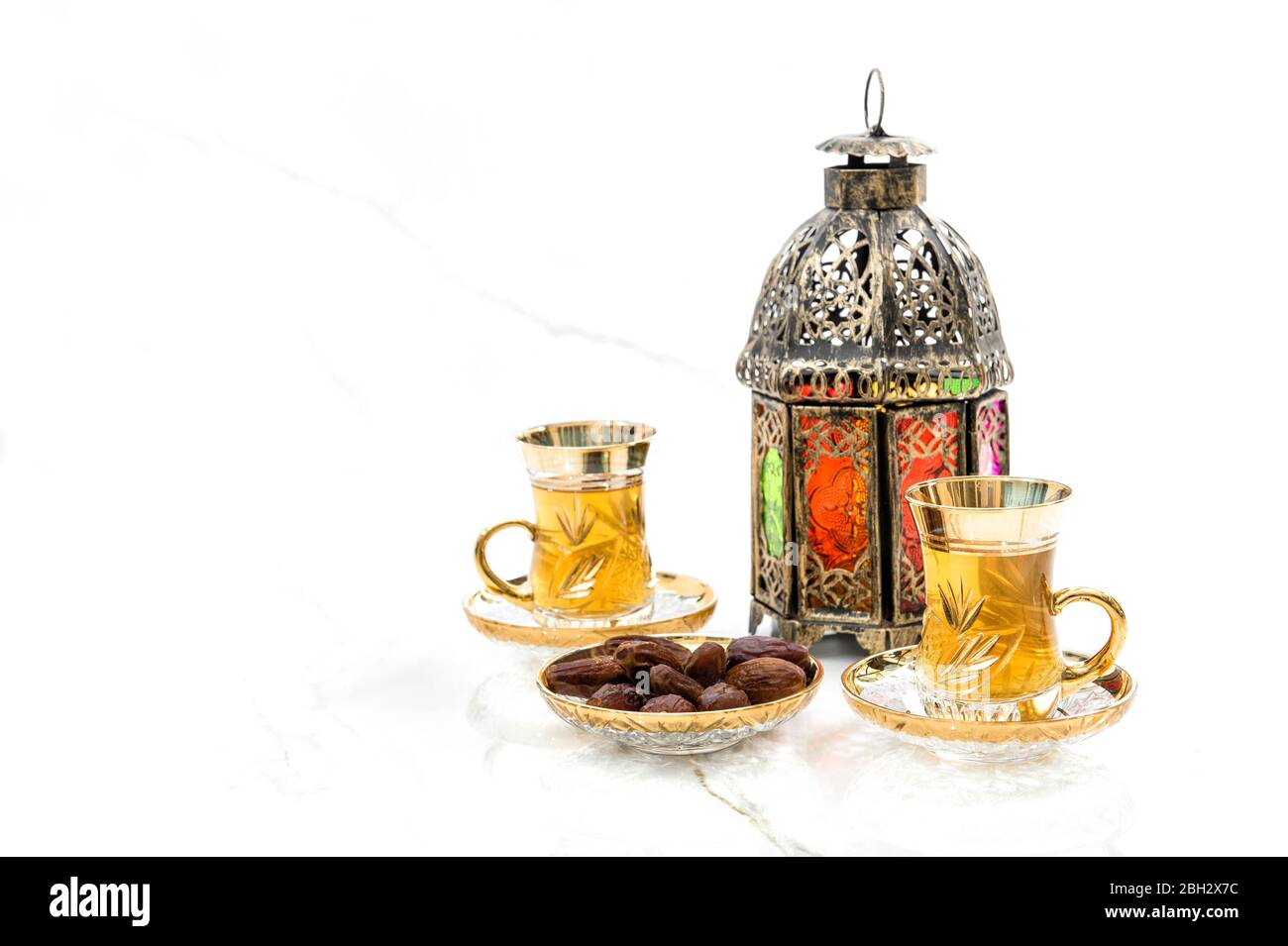 Teegläser mit Datteln und orientalischer Laterne-Dekoration auf weißem Hintergrund Stockfoto
