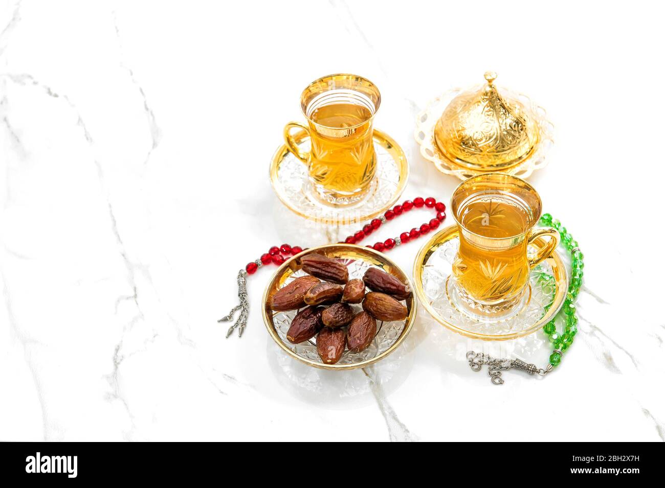 Teebecher mit Datteln und Rosenkranz auf weißem Hintergrund. Ramadan kareem Stockfoto