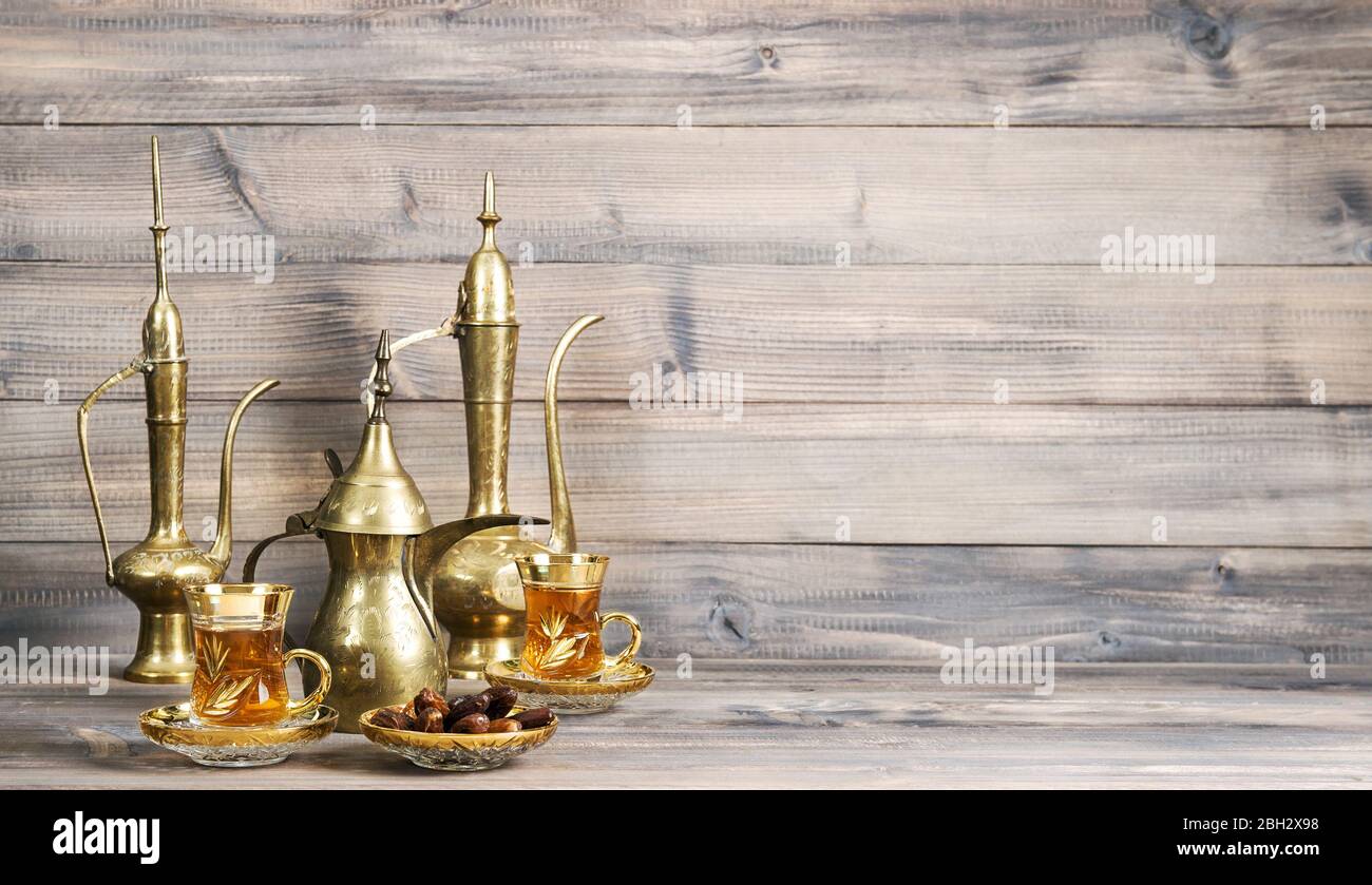 Teetafel mit Datteln und goldener orientalischer Dekoration auf Holzhintergrund Stockfoto