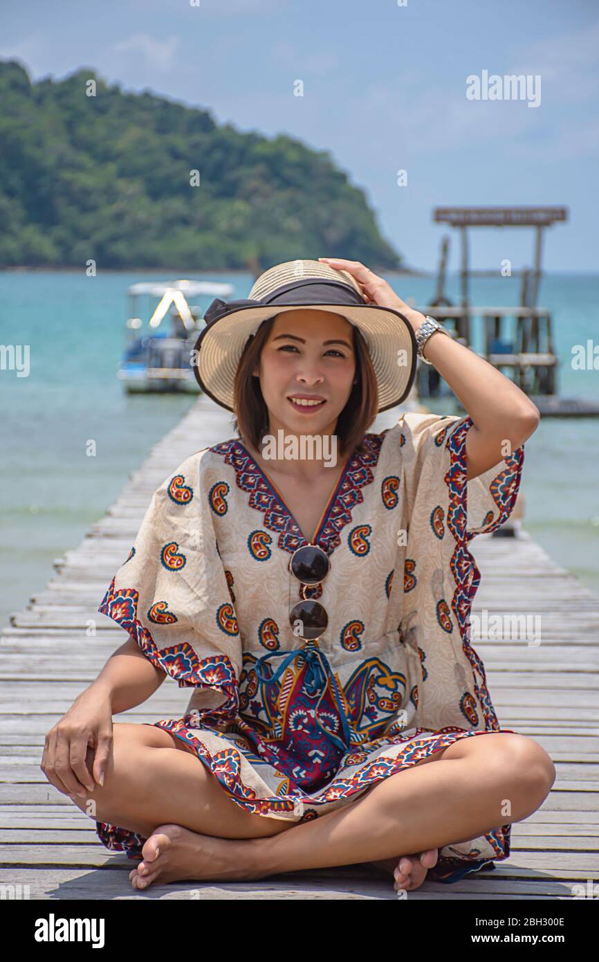 Frauen ein Hut auf dem hölzernen Brückenpfeiler Boot im Meer und dem hellen Himmel auf Koh Kood, trat in Thailand tragen. Stockfoto