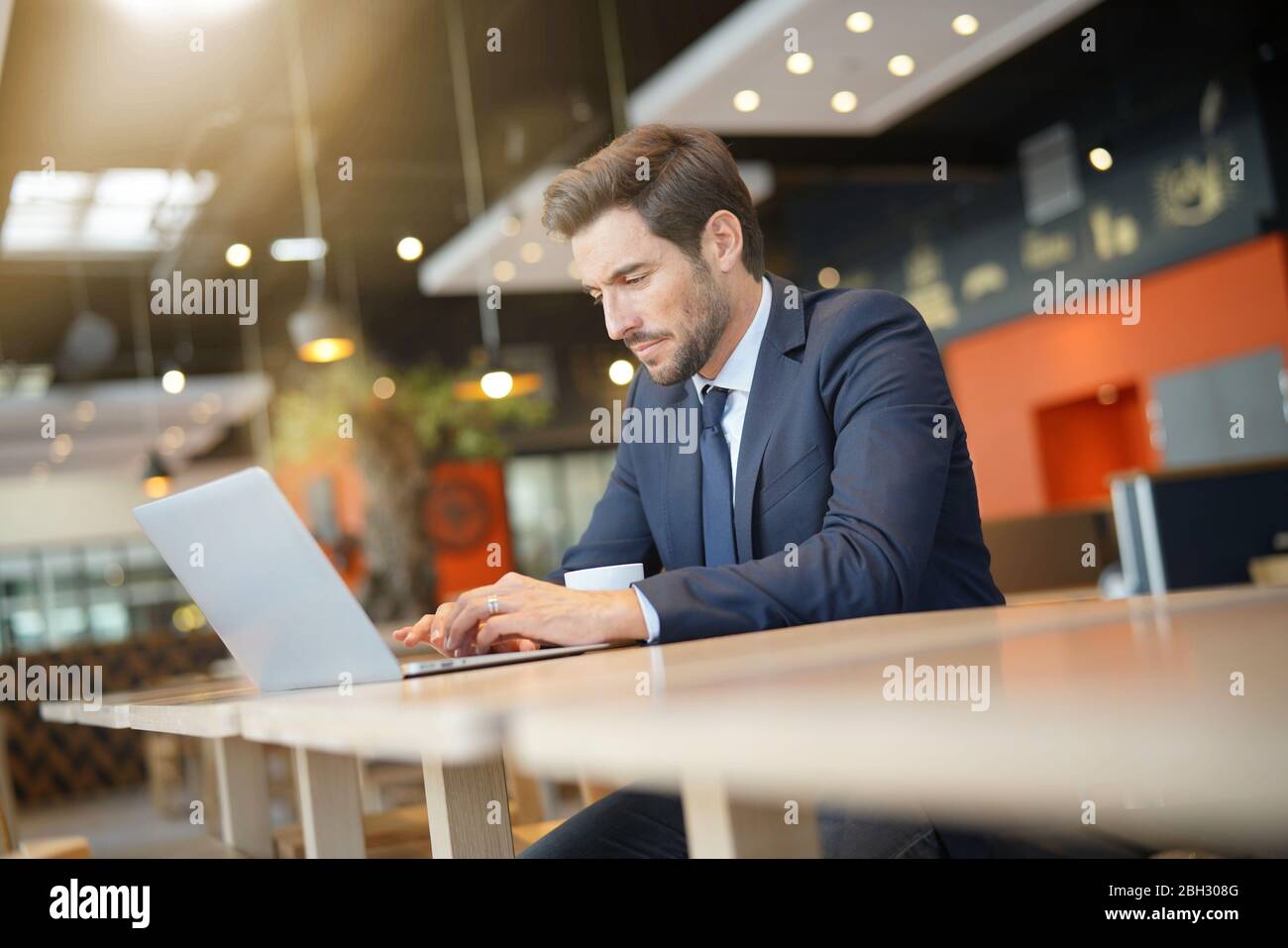 Unternehmer Arbeiten am Laptop, während sie darauf warten, Kunden zu erfüllen Stockfoto