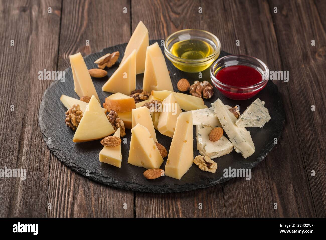 Verschiedene Käsesorten auf einem schwarzen Gericht. Serviert mit Nußsauce und Honig. Stockfoto