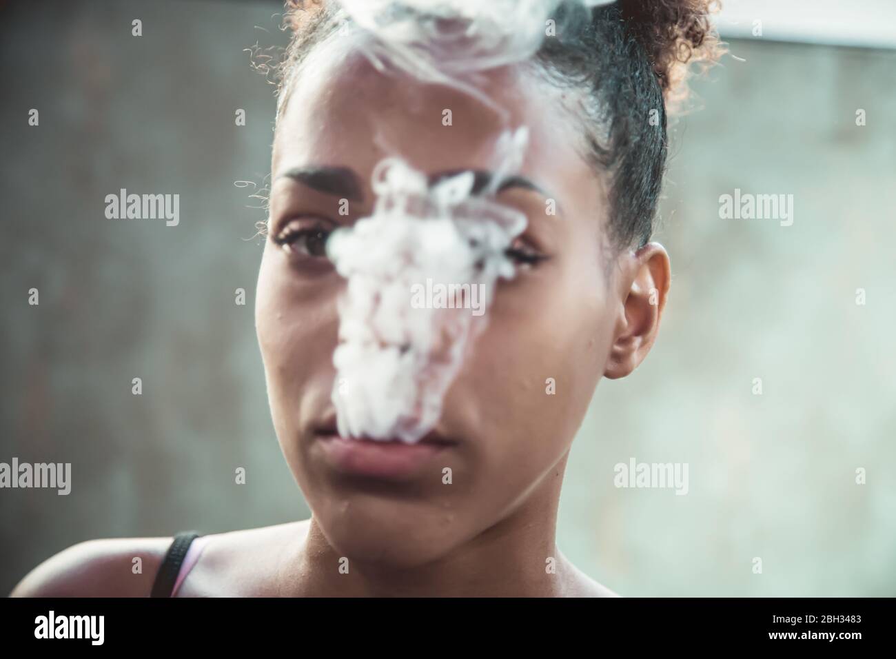 Porträt eines schwarzen Mädchens, das Rauch aus dem Mund zieht Stockfoto