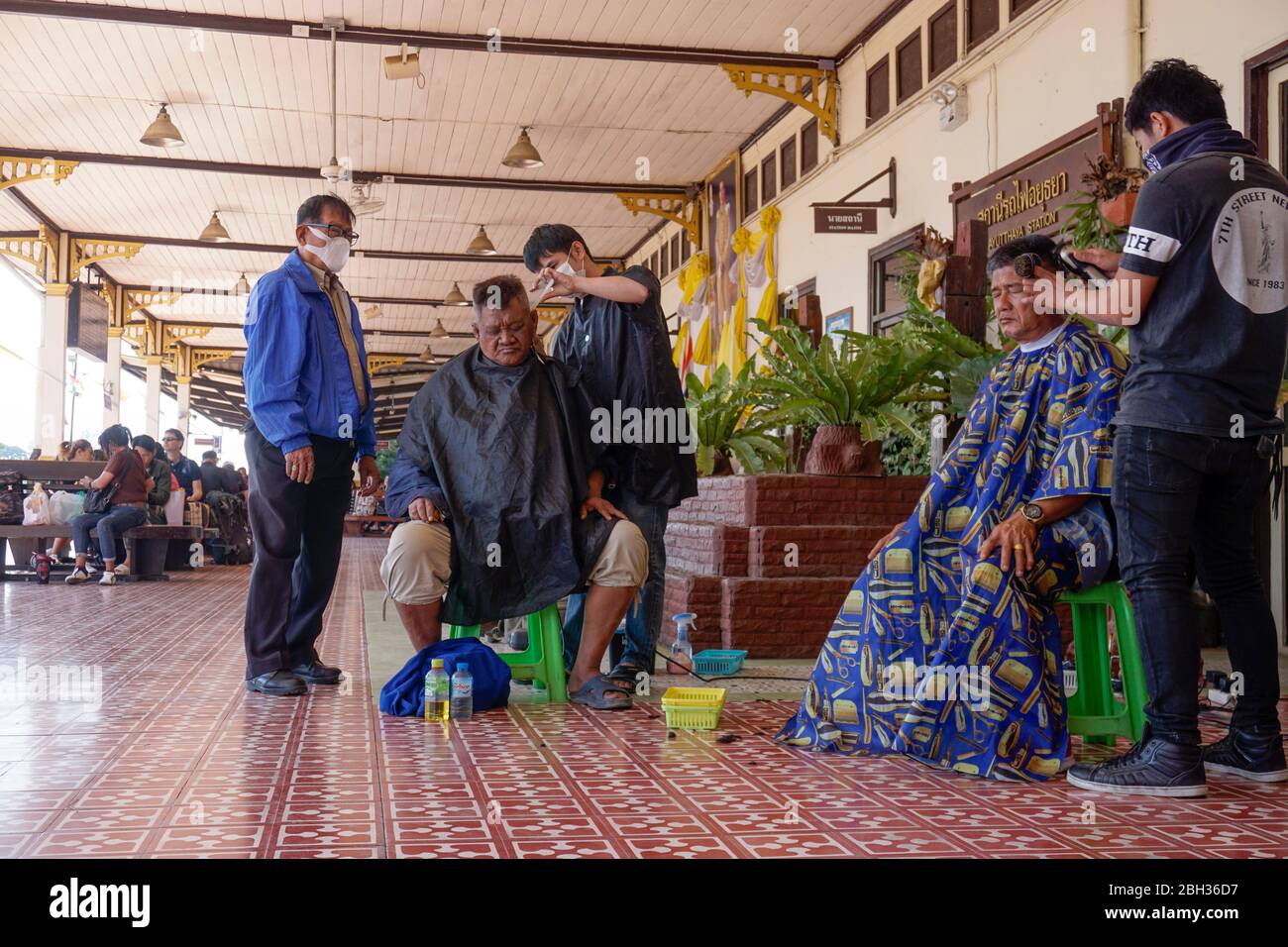 Friseur mit Gesichtsmasken im Bahnhof in Ayutthaya, Thailand Stockfoto