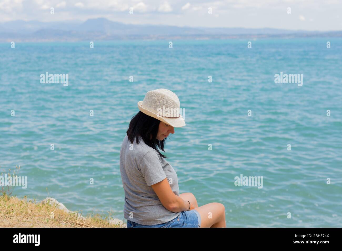Schöne Lifestyle-Frau sitzt und am Ufer des Sees entspannen Kontemplation erstaunliche Landschaft. Familienurlaub im Sommer. Entspannen. Glück Stockfoto