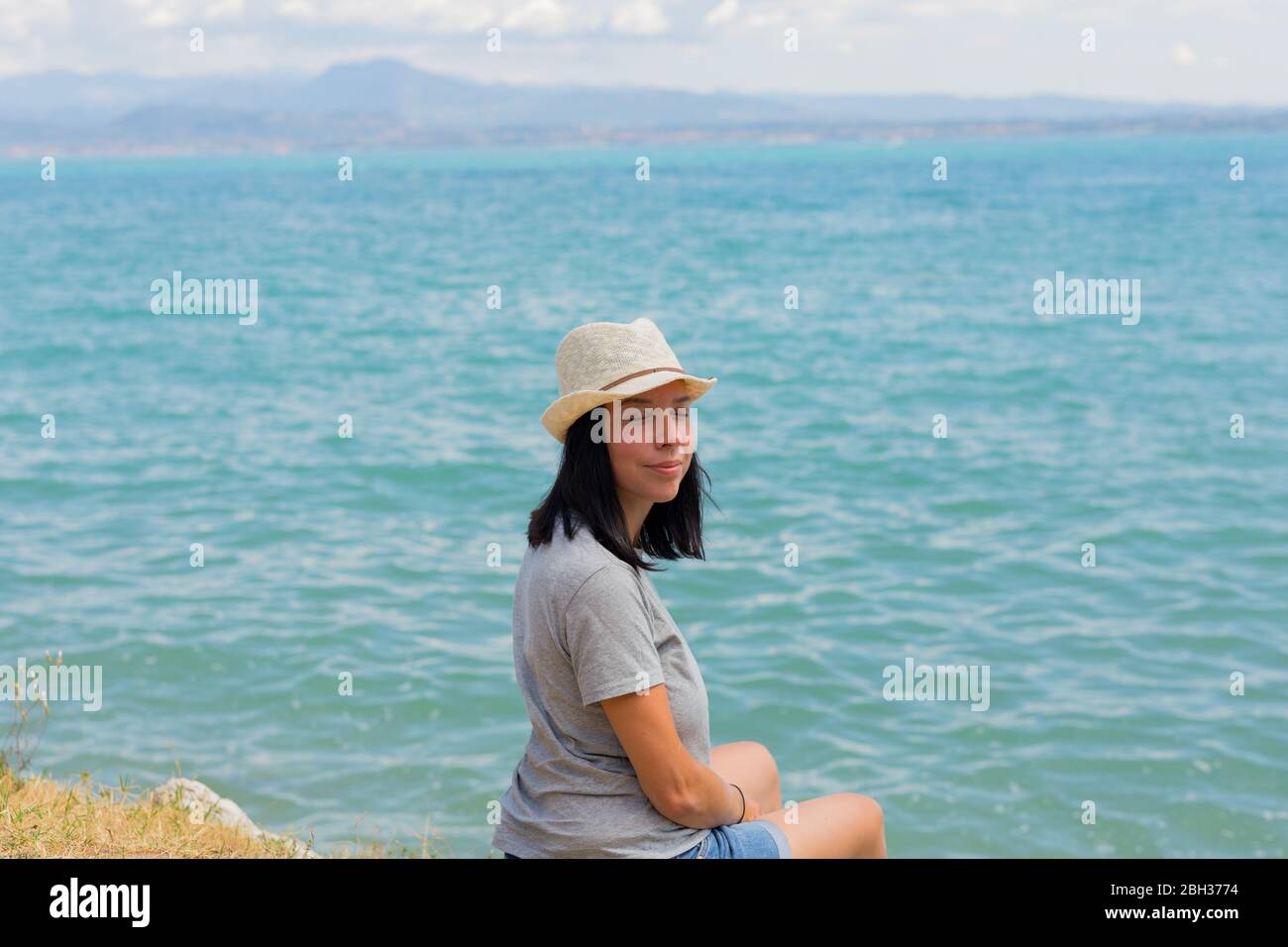 Schöne Lifestyle-Frau sitzt und am Ufer des Sees entspannen Kontemplation erstaunliche Landschaft. Familienurlaub im Sommer. Entspannen. Glück Stockfoto