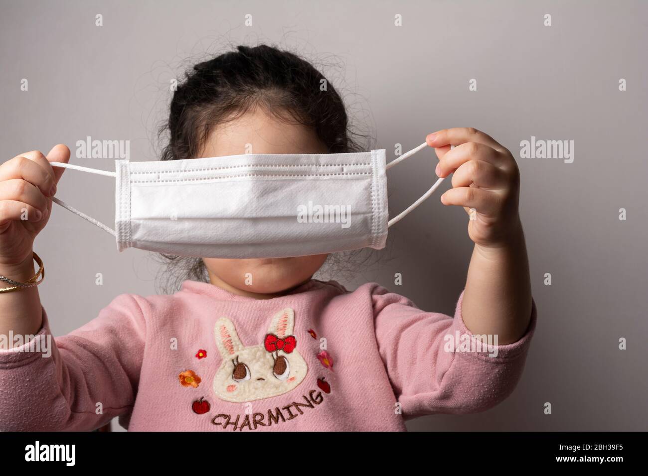Kleines Mädchen, das versucht, eine Maske zum Schutz vor Epidemie Coronavirus, Coronavirus Ausbruch und Luftverschmutzung Konzept tragen Stockfoto