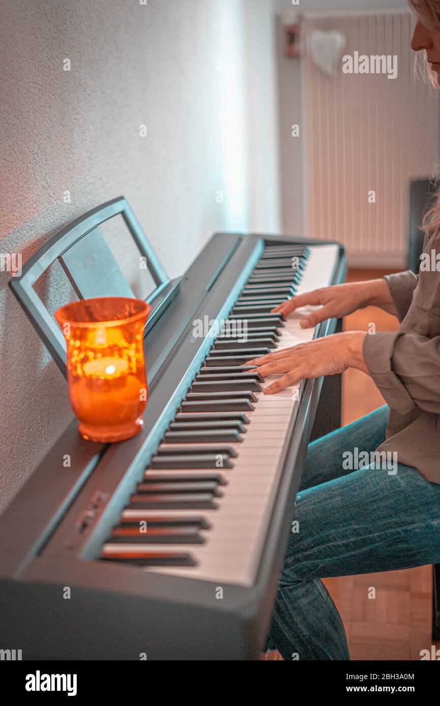 Hübsche Frau spielt zu Hause an beengten Tagen Klavier Stockfoto