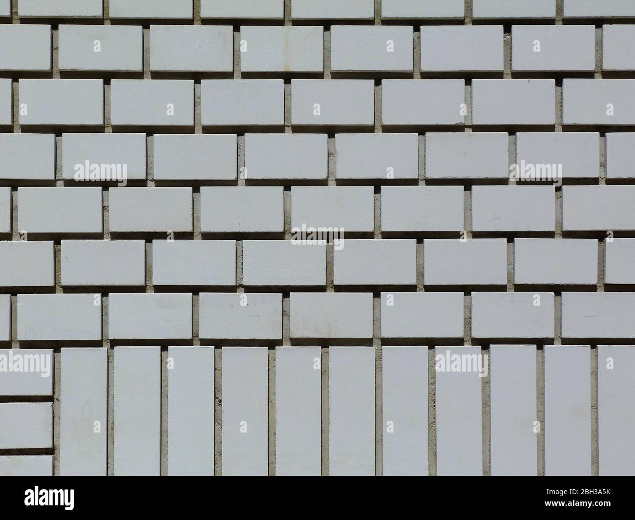 Weiße Ziegelwand Höhe Detail. Tiefe Mörtel Gelenke und Schatten. Laufende Bindung und Teil Header Kurs. Backstein Muster Konzept. Backstein Wand Textur. Stockfoto