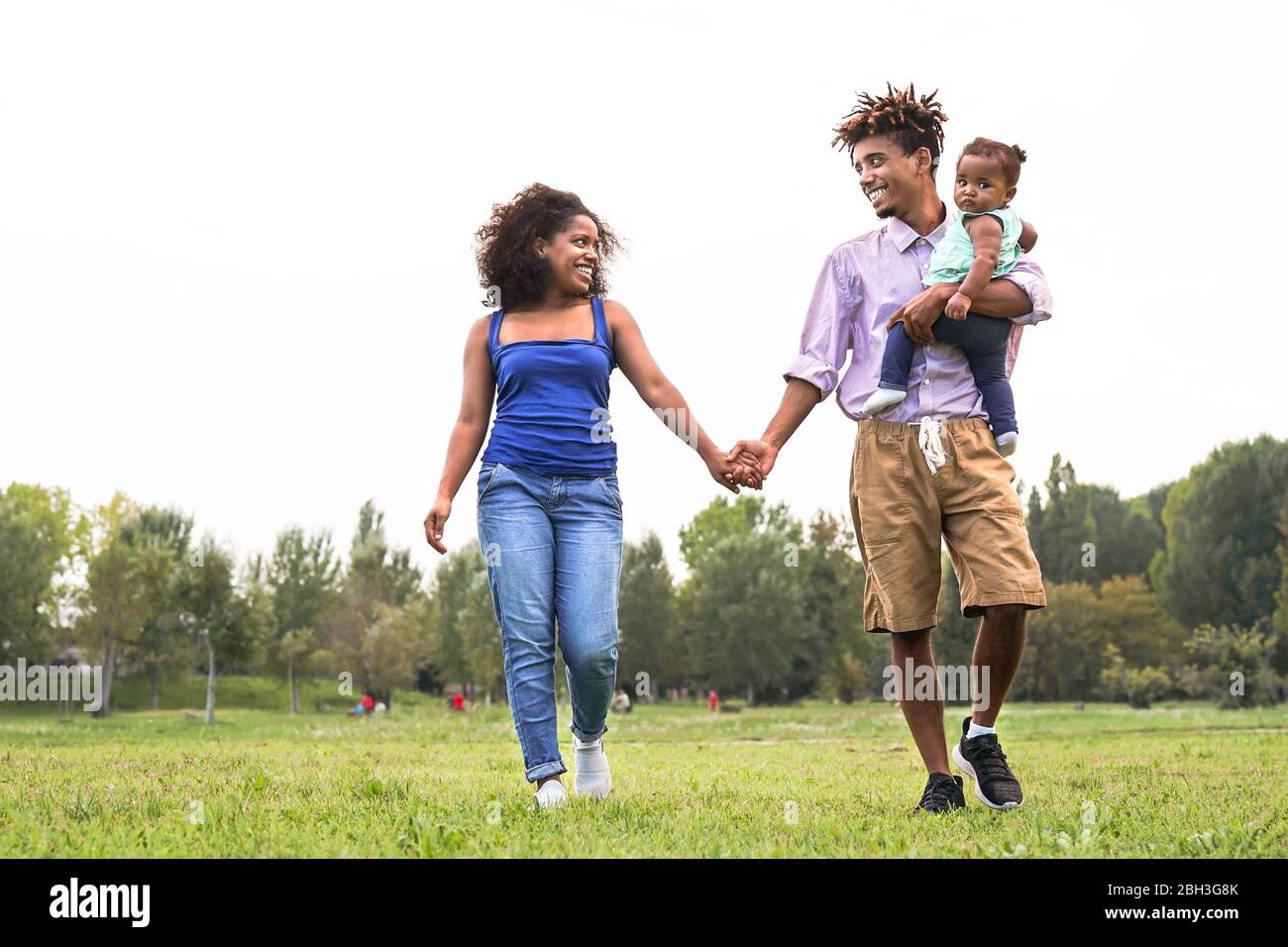 Glückliche afrikanische Familie hat Spaß im öffentlichen Park - Mutter und Vater mit ihrer Tochter genießen zusammen am Wochenende im Freien Stockfoto