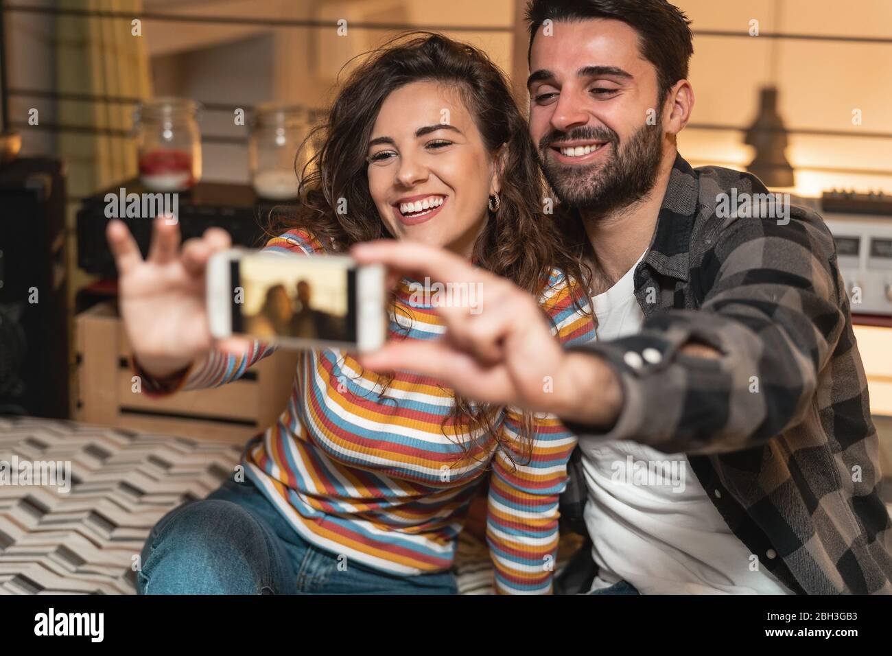 Glückliches Paar Selfie mit dem mobilen Smartphone im Wohnzimmer zu Hause - Junge Liebhaber haben Spaß mit neuen trendigen Social-Media-Apps Stockfoto