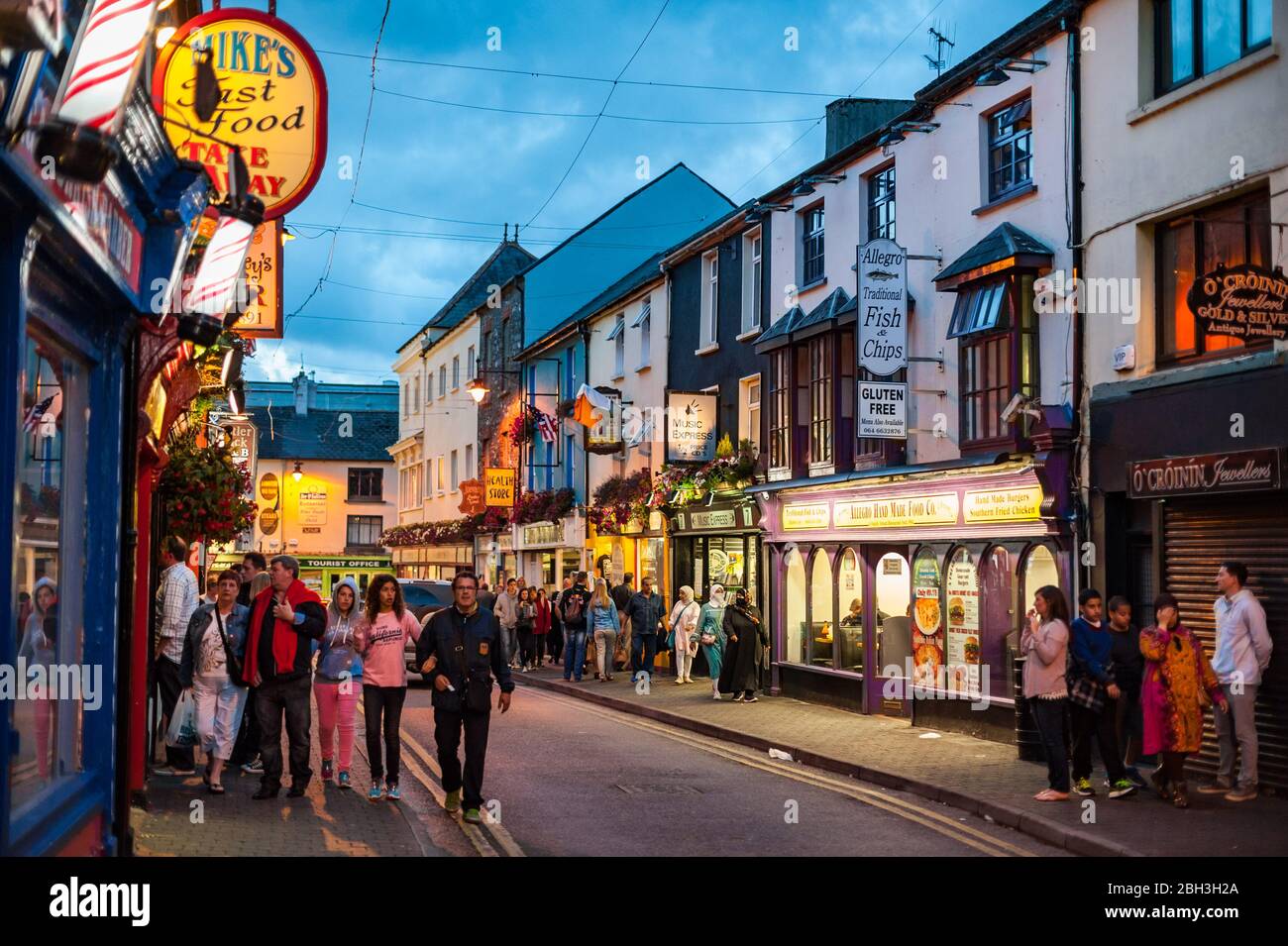 Killarney, Irland - 16. März 2018: Menschen, die in der Abenddämmerung durch die belebten Straßen von Killarney gehen. Killarney ist ein beliebtes landschaftlich reizvoller Touristenziel in Stockfoto