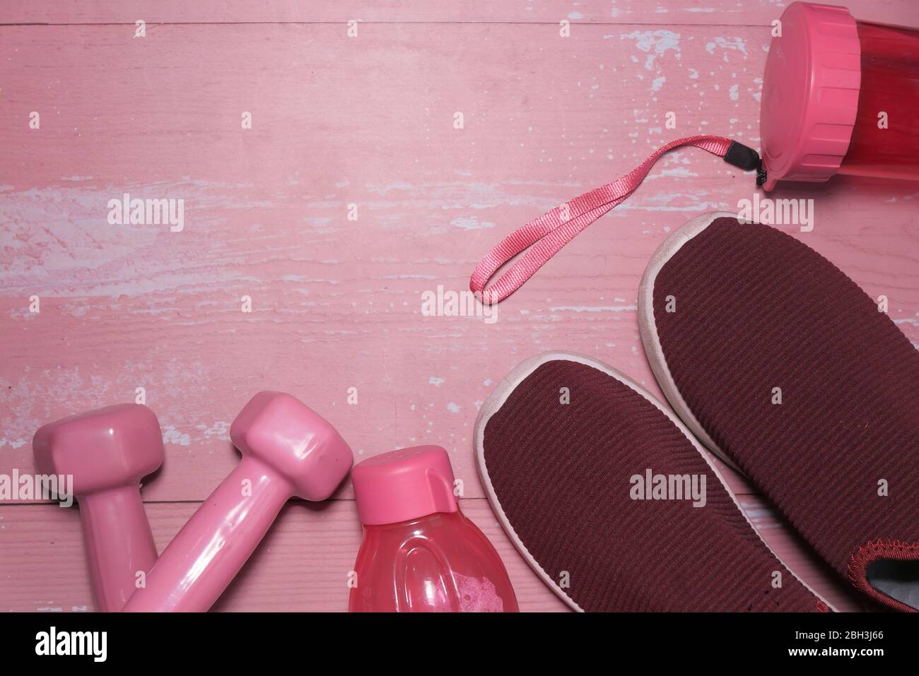 Nahaufnahme der rosa Farbe Hantel und Glas Wasser auf dem Tisch Stockfoto