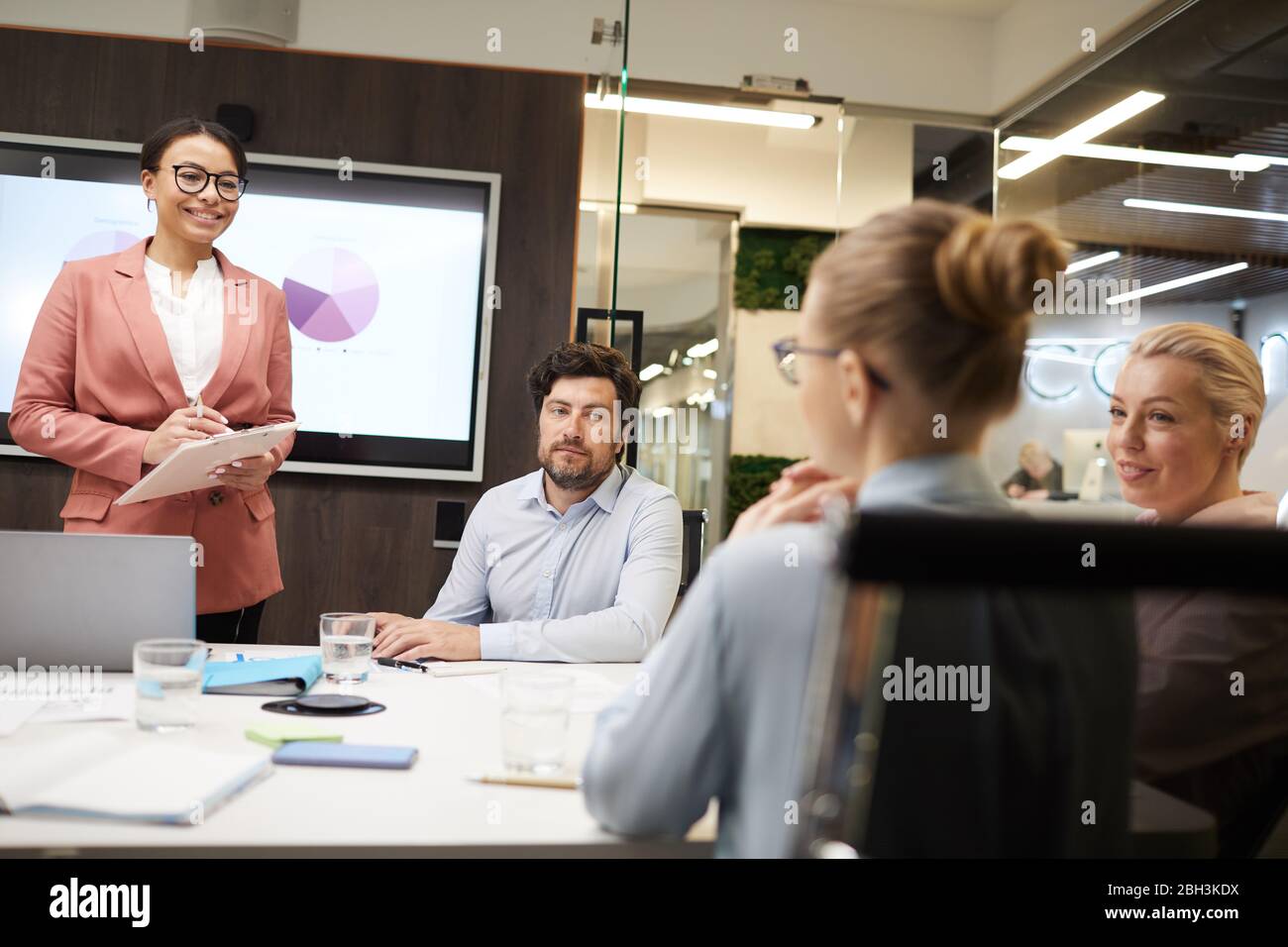 Geschäftsleute sitzen am Tisch und hören Geschäftsfrau während der Business-Ausbildung im Büro Stockfoto