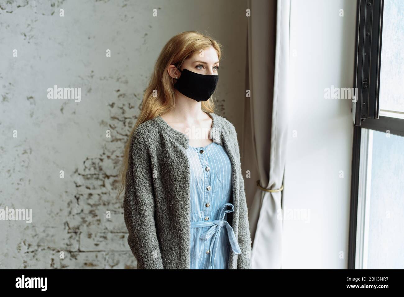 Traurige einsame Mädchen zu Hause in schützende sterile medizinische Maske auf ihrem Gesicht isoliert Blick auf Fenster, gelangweilte Frau wegen der chinesischen Pandemie Coronavirus, Virus Covid-19. Quarantäne, Infektion verhindern. Stockfoto