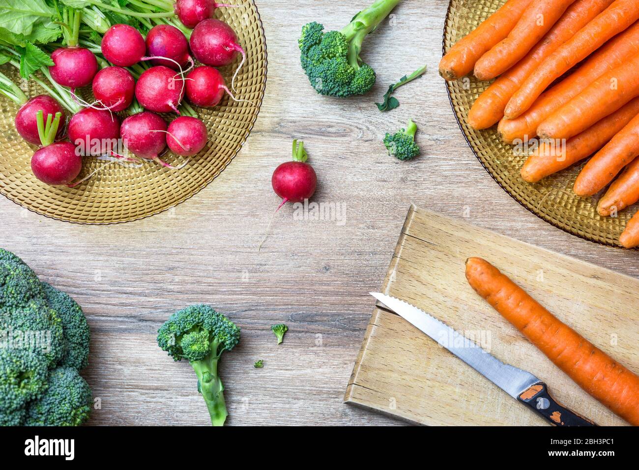 Frische Bio-rote Radieschen, Karotten und Brokkoli auf Holzhintergrund. Draufsicht mit Kopierbereich. Gesundes Ernährungskonzept. Stockfoto