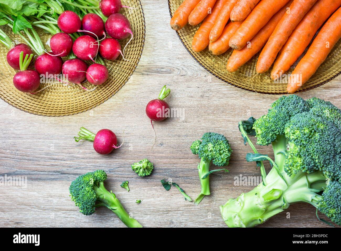 Frische Bio-rote Radieschen, Karotten und Brokkoli auf Holzhintergrund. Draufsicht mit Kopierbereich. Gesundes Ernährungskonzept. Stockfoto