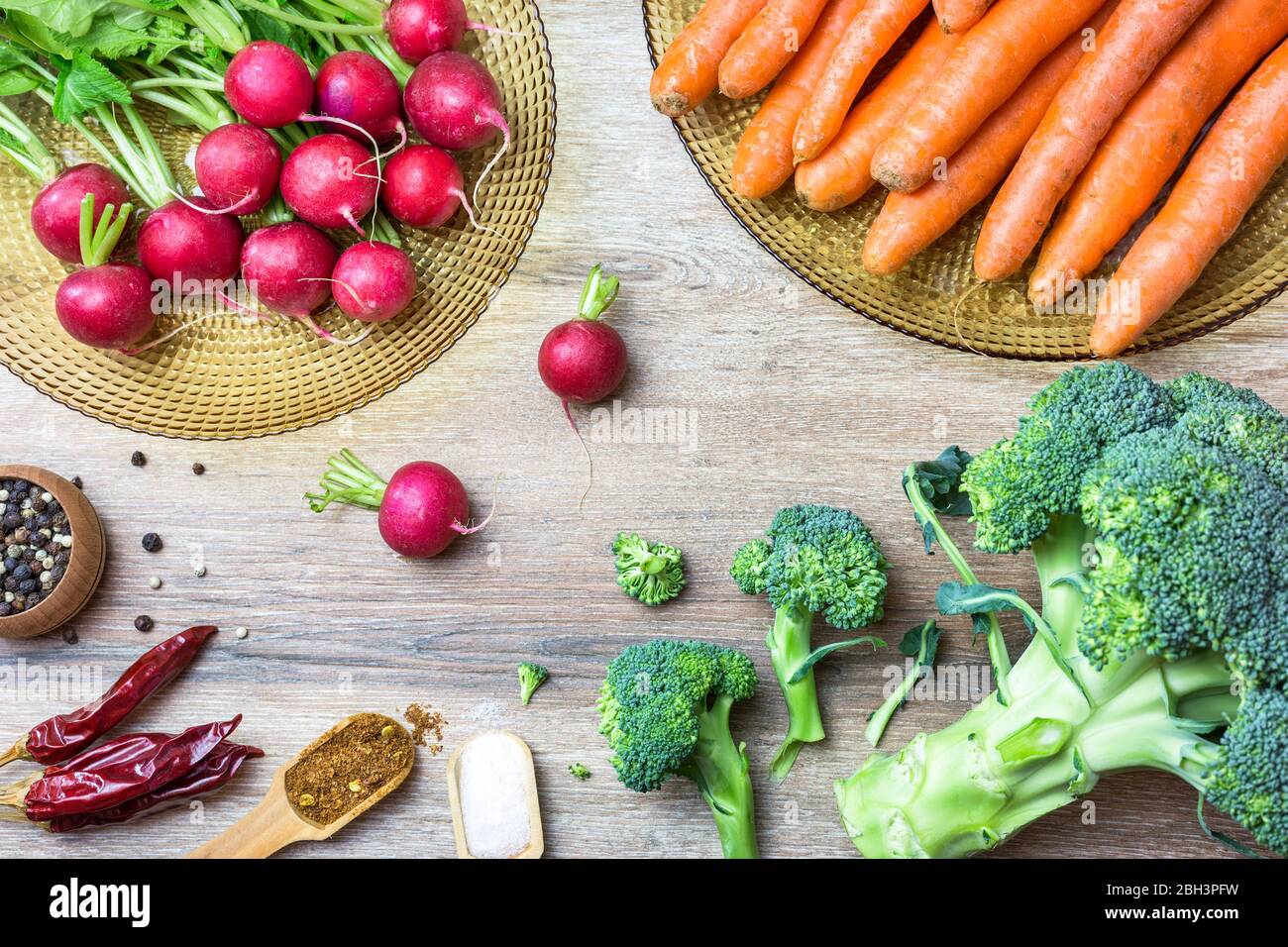 Frische Bio-rote Radieschen, Karotten, Brokkoli und Gewürze auf Holzhintergrund. Draufsicht mit Kopierbereich. Gesundes Ernährungskonzept. Stockfoto