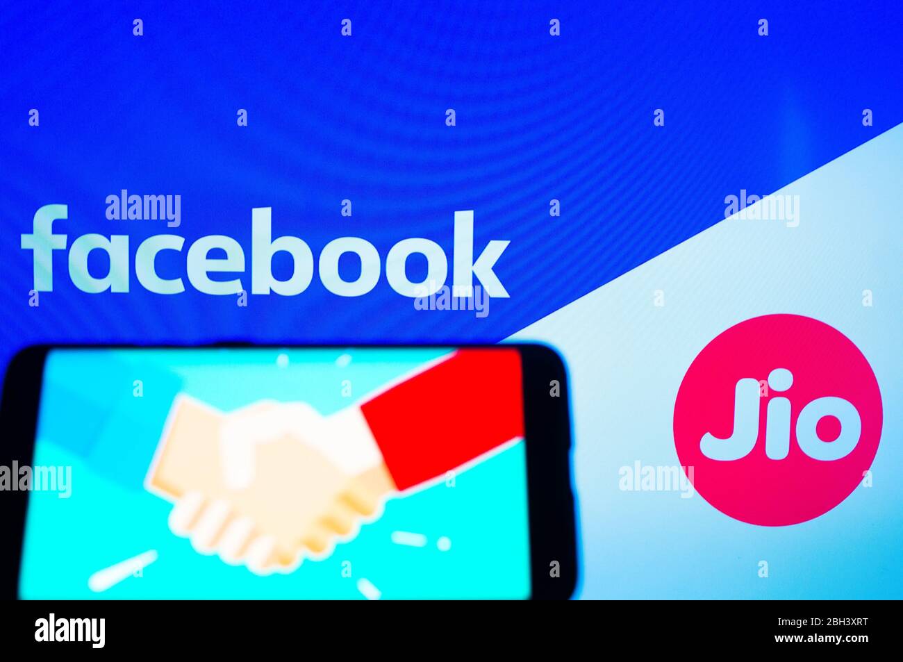 Handy mit Handshake-Bildschirm und facebook und jio im Hintergrund Stockfoto