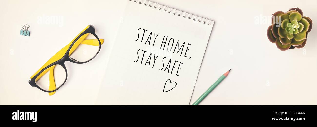 Worte bleiben zu Hause, bleiben Sie sicher in Notizbuch geschrieben, Konzept der Selbstquarantäne zu Hause als vorbeugende Virus Flat Lay Banner Stockfoto