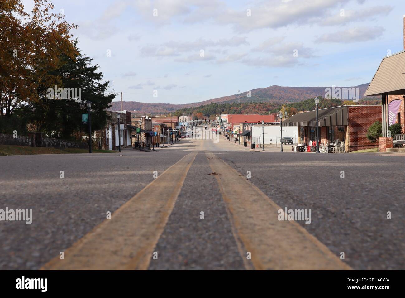 Ein Blick auf die Straße, die eine kleine Hauptstraße der Stadt, Mena Street, Mena, Arkansas, mit Herbstfarben auf Rich Mountain im Hintergrund Stockfoto