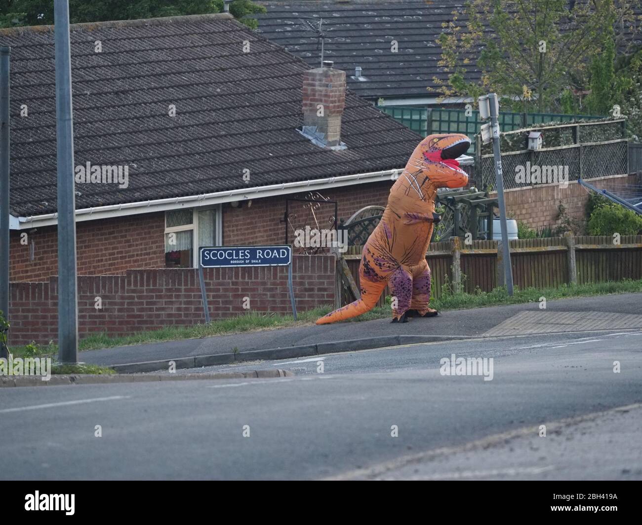 Minster on Sea, Kent, Großbritannien. April 2020. Eine Person in einem Dinosaurier-Kostüm klatscht für den NHS und kaufte sich heute Abend in Minster on Sea, Kent, ein Lächeln und einen Ruß von vorbeifahrenden Fahrern. Quelle: James Bell/Alamy Live News Stockfoto