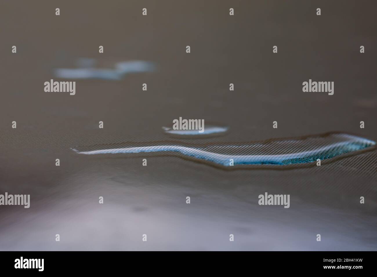 Schöne blaue Wirkung von Licht auf Wassertropfen auf einem Polycarbonat-Tisch im Garten Stockfoto