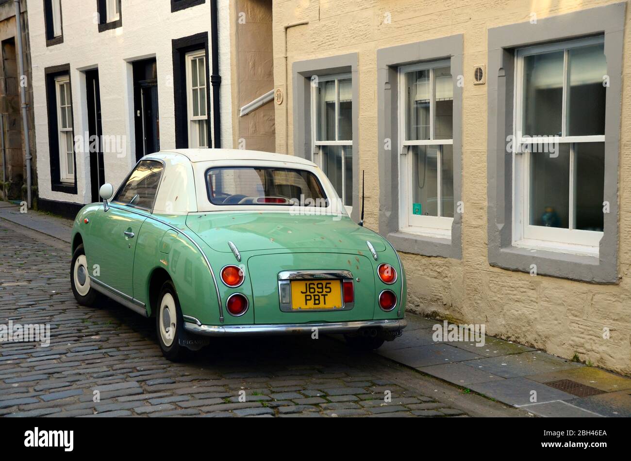Der Nissan Figaro, der im Retro-Stil der 1960er Jahre gebaut wurde, parkte auf einer gepflasterten Straße in der Altstadt von St andrews, Fife, Schottland Stockfoto
