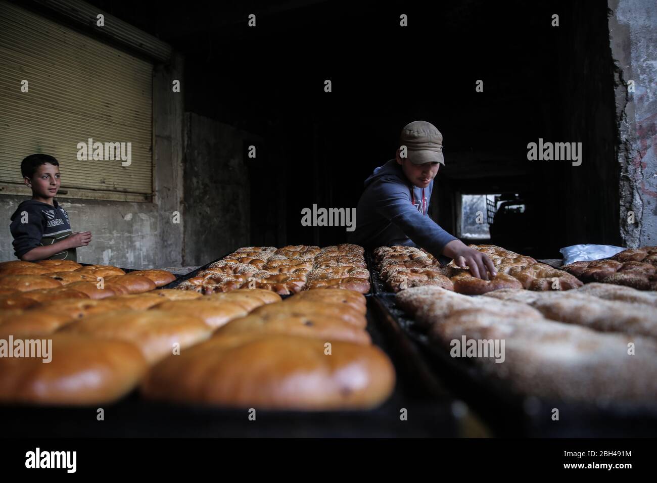 Idlib City, Syrien. April 2020. Ein syrischer junger Mann pflückt Gebäck auf einem Straßenmarkt, während Muslime am Vorabend des heiligen Fastenmonats des Muslims Ramadan Lebensmittel und Vorräte einkaufen. Quelle: Anas Alkharboutli/dpa/Alamy Live News Stockfoto