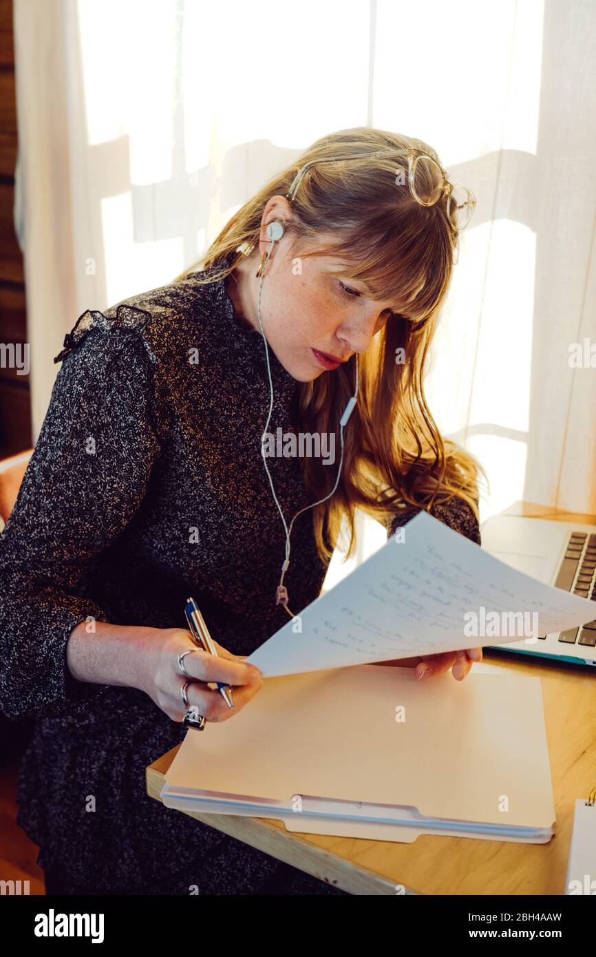 Geschäftsfrau, die auf Laptop-Computer Notizen und läuft ihr Geschäft von zu Hause aus während der covid-19 zu Hause bleiben bestellen. Covid-19-Pandemie Stockfoto