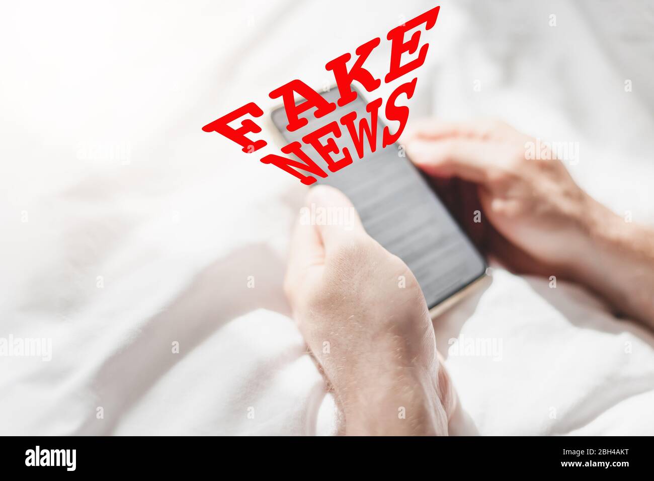 Fake News Infosemics during Covid-19 Pandemie Concept. Mann hält Handy und liest zu Hause Nachrichten oder soziale Netzwerke. Letzte News lesen upd Stockfoto