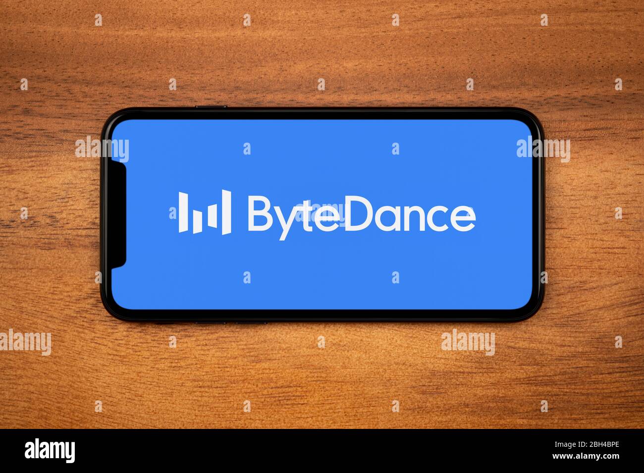 Ein Smartphone mit dem Bytedance Logo liegt auf einem einfachen Holztisch (nur für redaktionelle Verwendung). Stockfoto