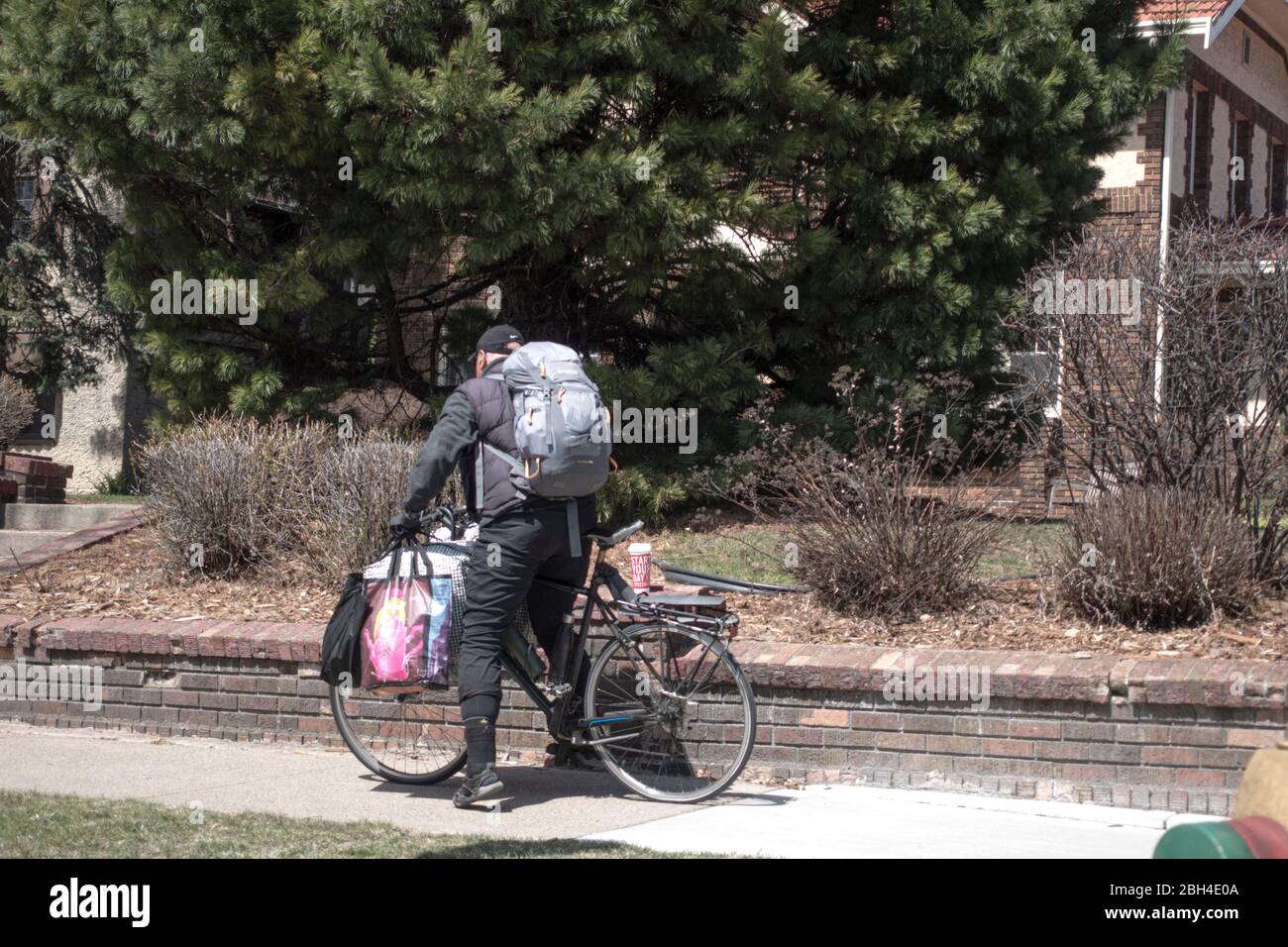 Mann auf Fahrrad mit Paketen beladen. Während der Pandemie von Covid-19 könnte es Obdachlos sein oder Nahrungsmittel und Vorräte liefern. St. Paul Minnesota, USA Stockfoto