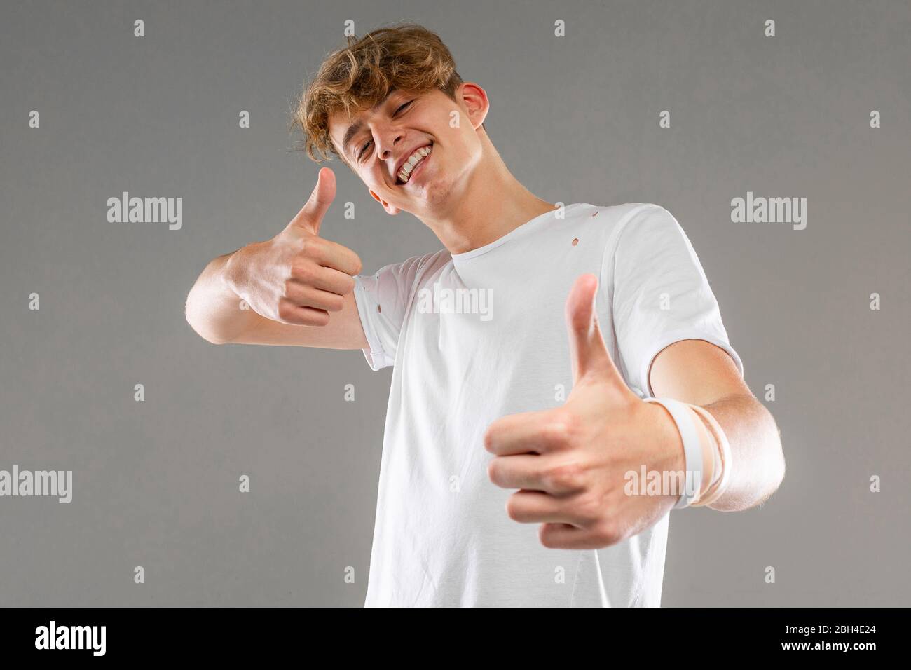 Happy kaukasischen Mann im weißen T-Shirt gestikulierend auf Kamera auf grauem Hintergrund Stockfoto